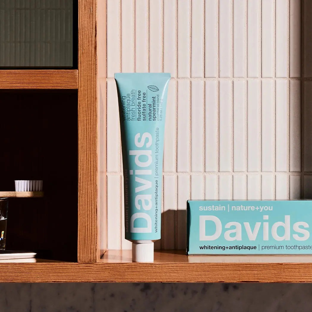Davids toothpaste tube and box on a wooden shelf with tiled wall background