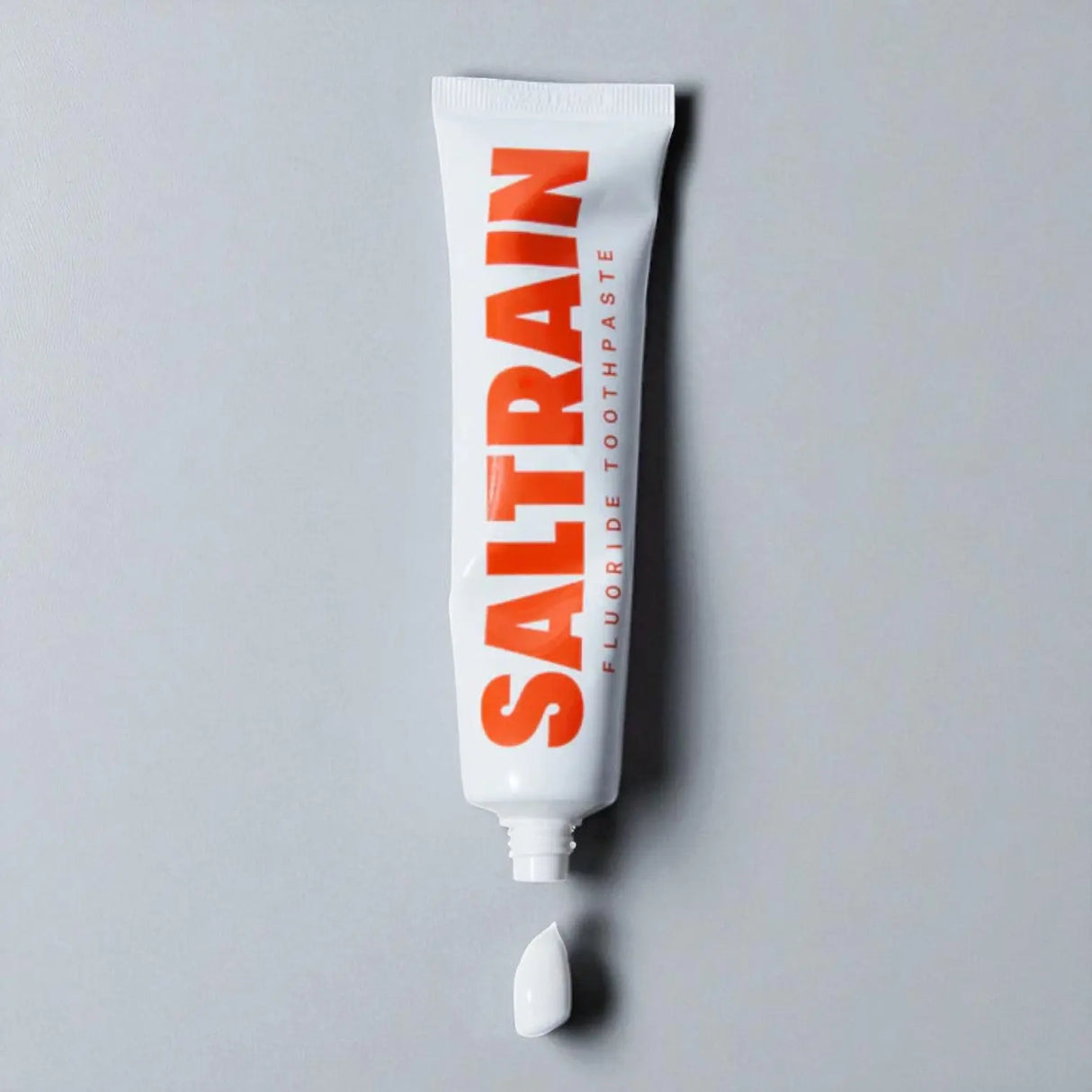 Saltrain fluoride toothpaste tube on a gray background