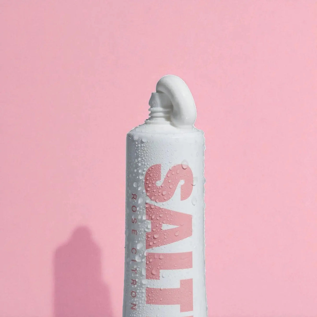 Close up of Saltrain Rose Citron Toothpaste on a pink background