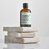 Bottle of Davids Oil Pulling Oral Rinse on a stack of stones with a light gray background