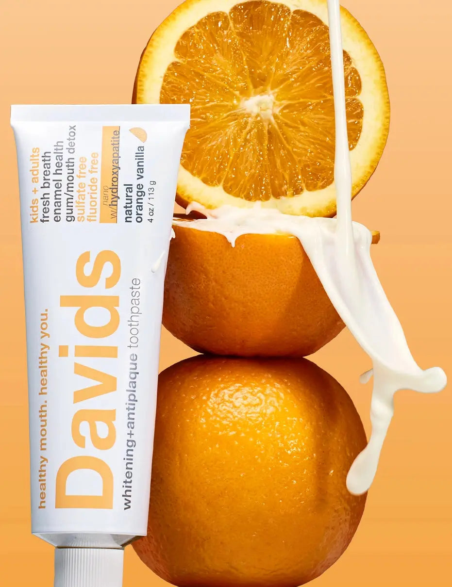 Davids toothpaste tube with an orange and milk on a reflective surface