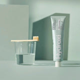 Tube of Davids Natural Toothpaste with a glass and toothbrush on a light background