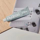 Tube of Davids Hydroxi toothpaste on a metallic surface with a wooden background