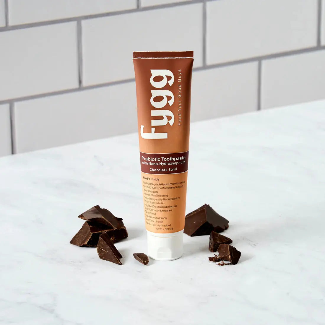 Fygg toothpaste tube with chocolate pieces on a white surface