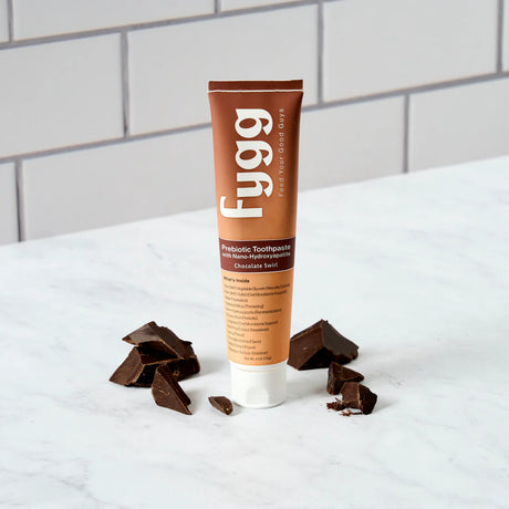 Fygg toothpaste tube with chocolate pieces on a white surface