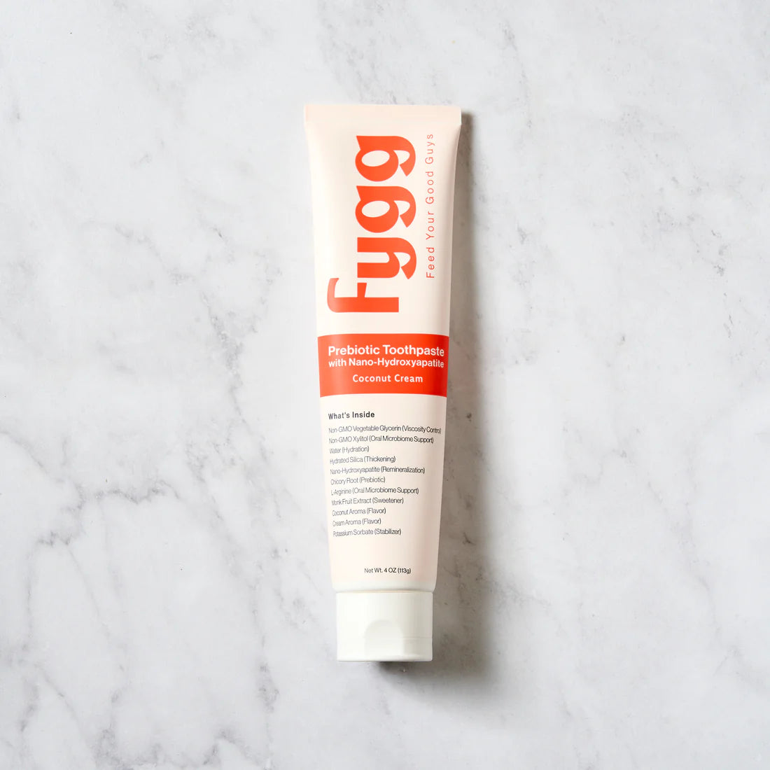 Fygg probiotic toothpaste tube on a marble background