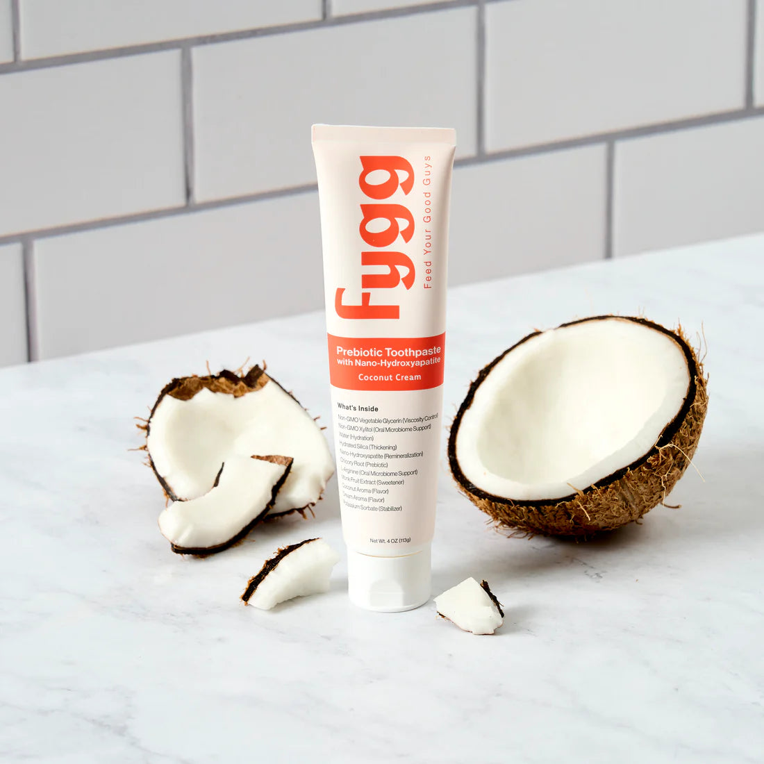 Fygg toothpaste tube with coconut halves on a white surface
