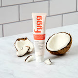 Fygg toothpaste tube with coconut halves on a white surface