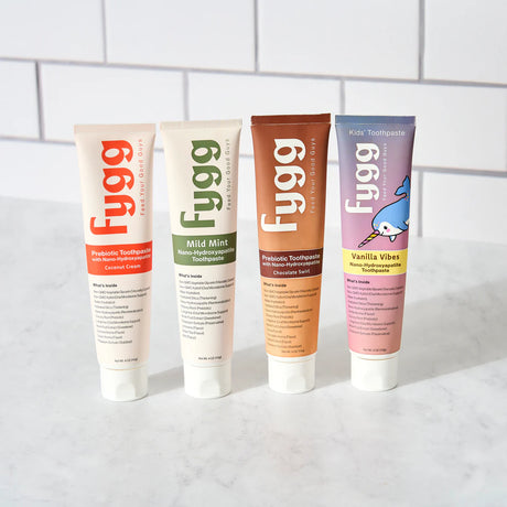 Four tubes of Fygg toothpaste on a white surface with a tiled wall background