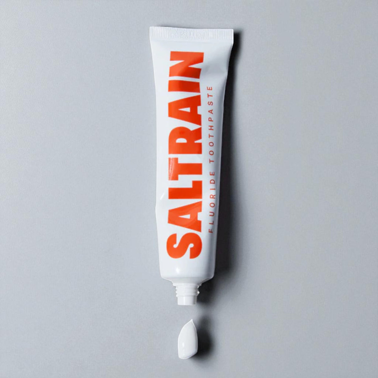 Saltrain fluoride toothpaste tube on a gray background
