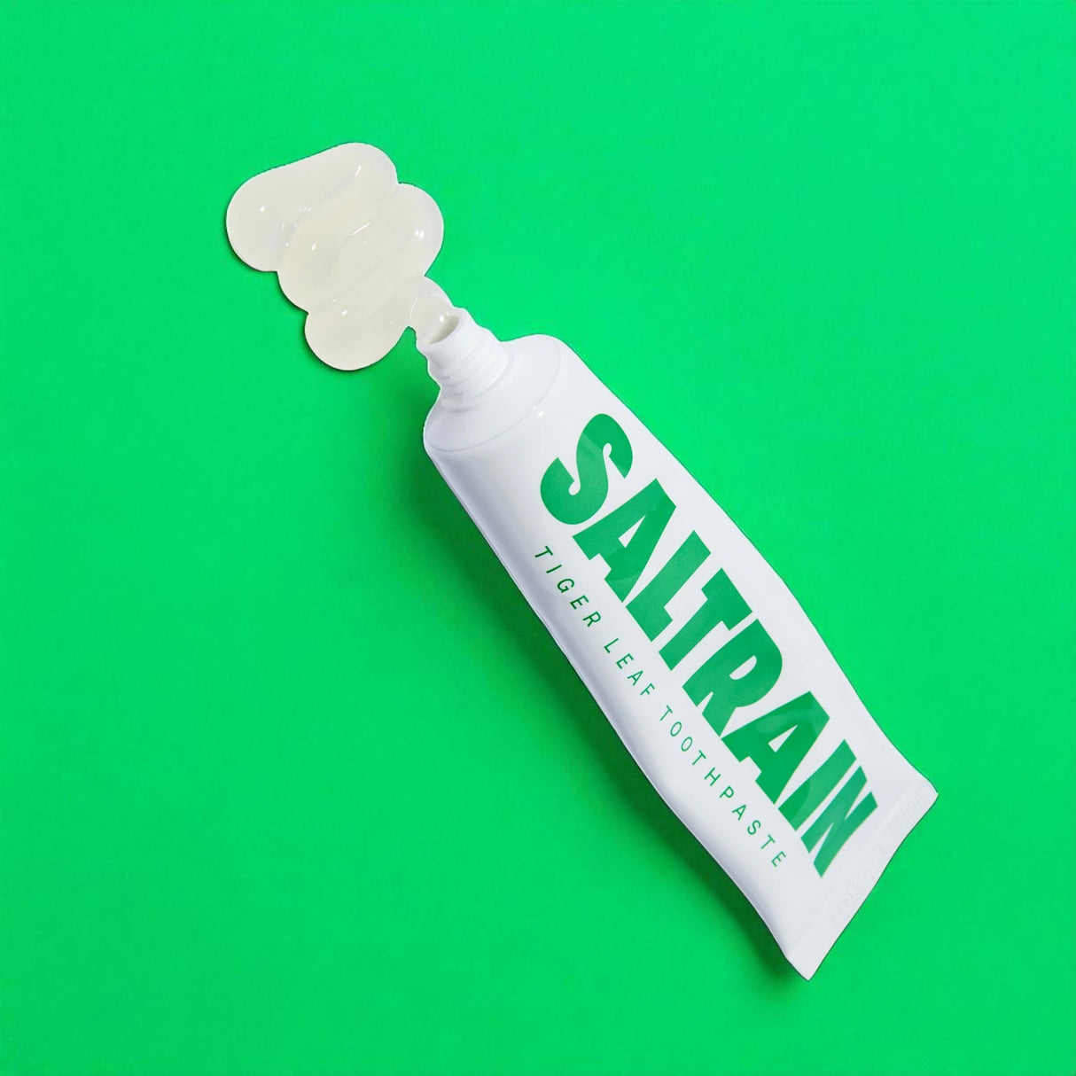 Saltrain toothpaste tube on a green background